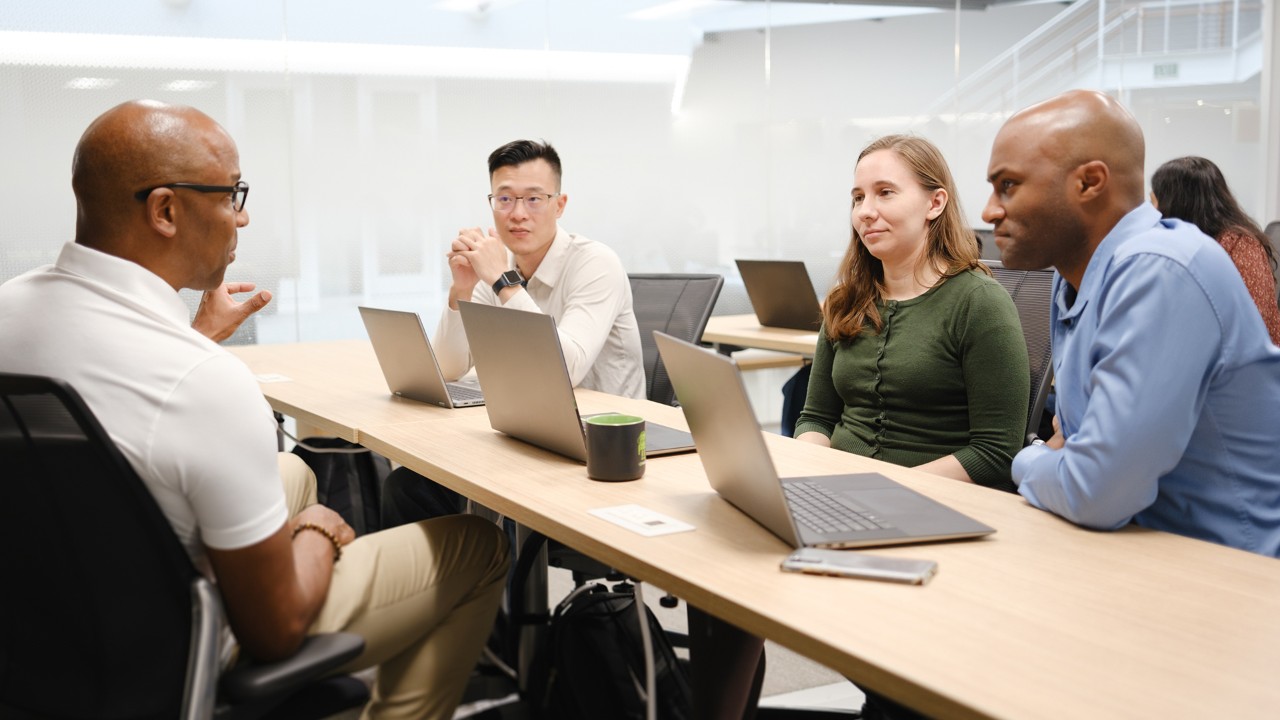 A group of business professionals discuss the expansion of AI access and training