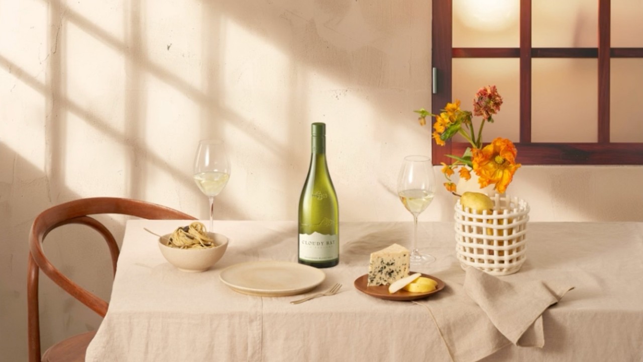 Table setting with wine, cheese, snacks, and flowers in warm natural light